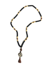 Carica l&#39;immagine nel visualizzatore di Gallery, Mala Tibetano in onice, legno e seme di Rudra con ciondolo in ottone e howlite con simbolo Ohm con nappina in cotone marrone
